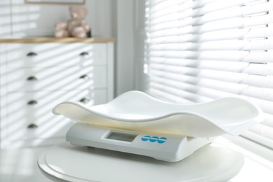 Modern digital baby scales on table in room