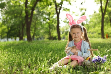 Photo of Little girl with Easter bunny and basket outdoors