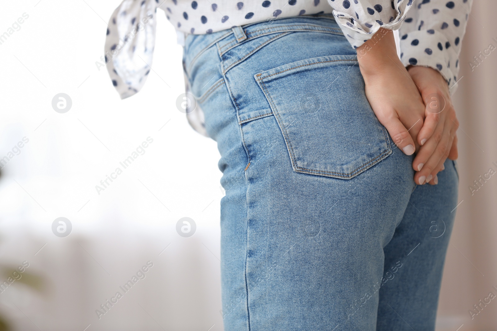 Photo of Young woman suffering from hemorrhoid at home, closeup