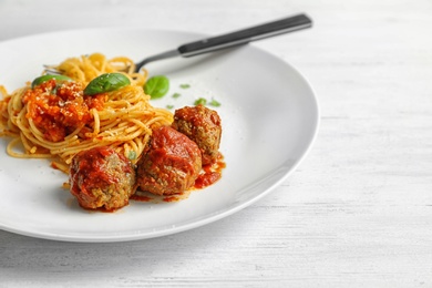 Delicious pasta with meatballs and tomato sauce on wooden background