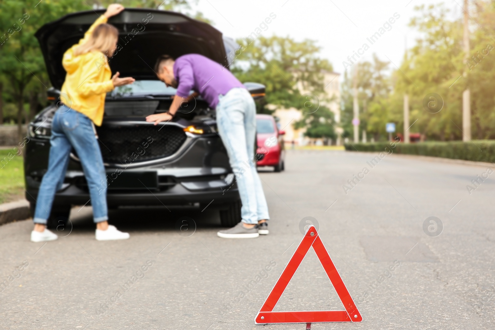 Photo of Emergency stop sign and people near broken car on background