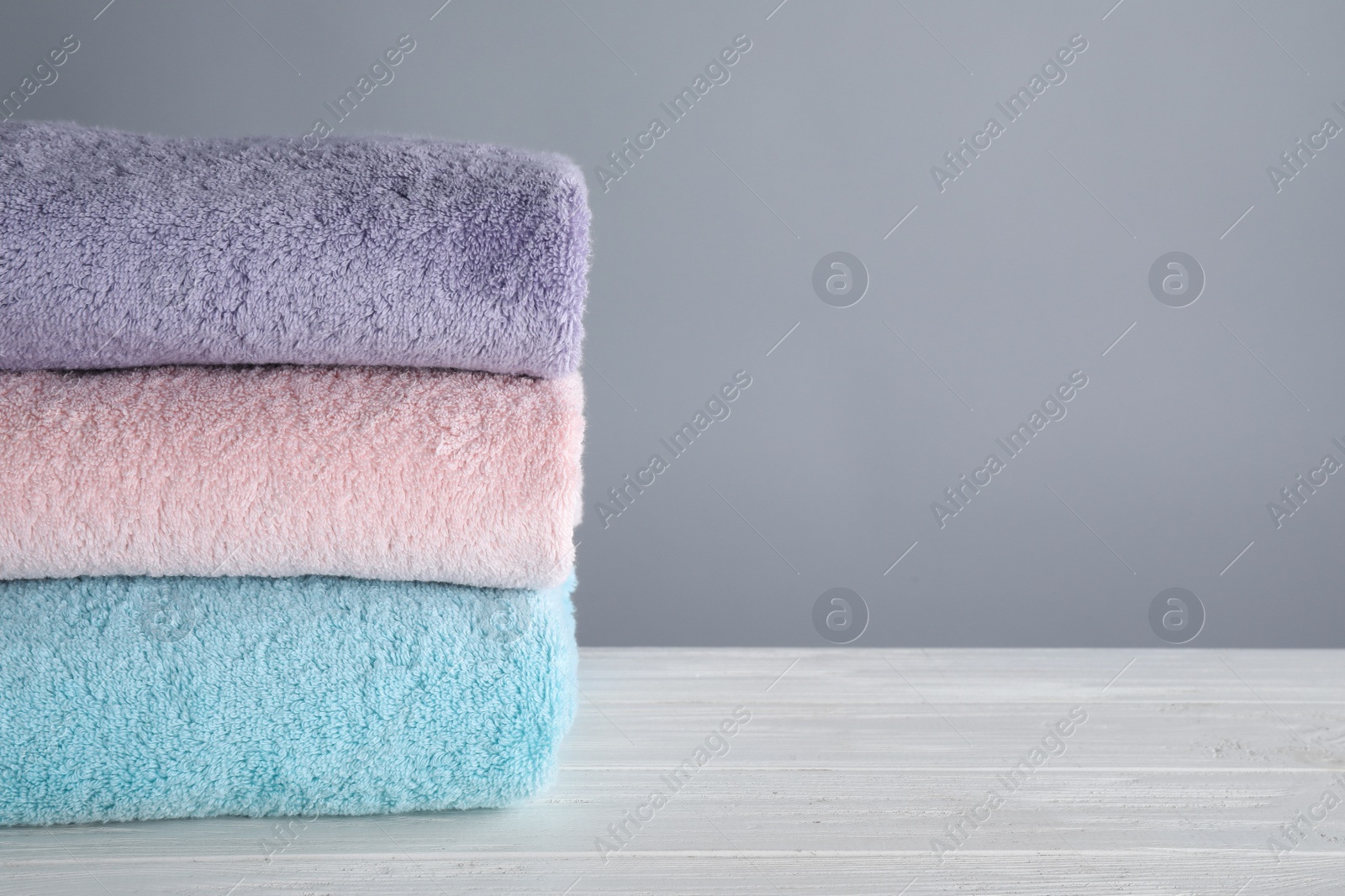 Photo of Fresh towels on wooden table, space for text