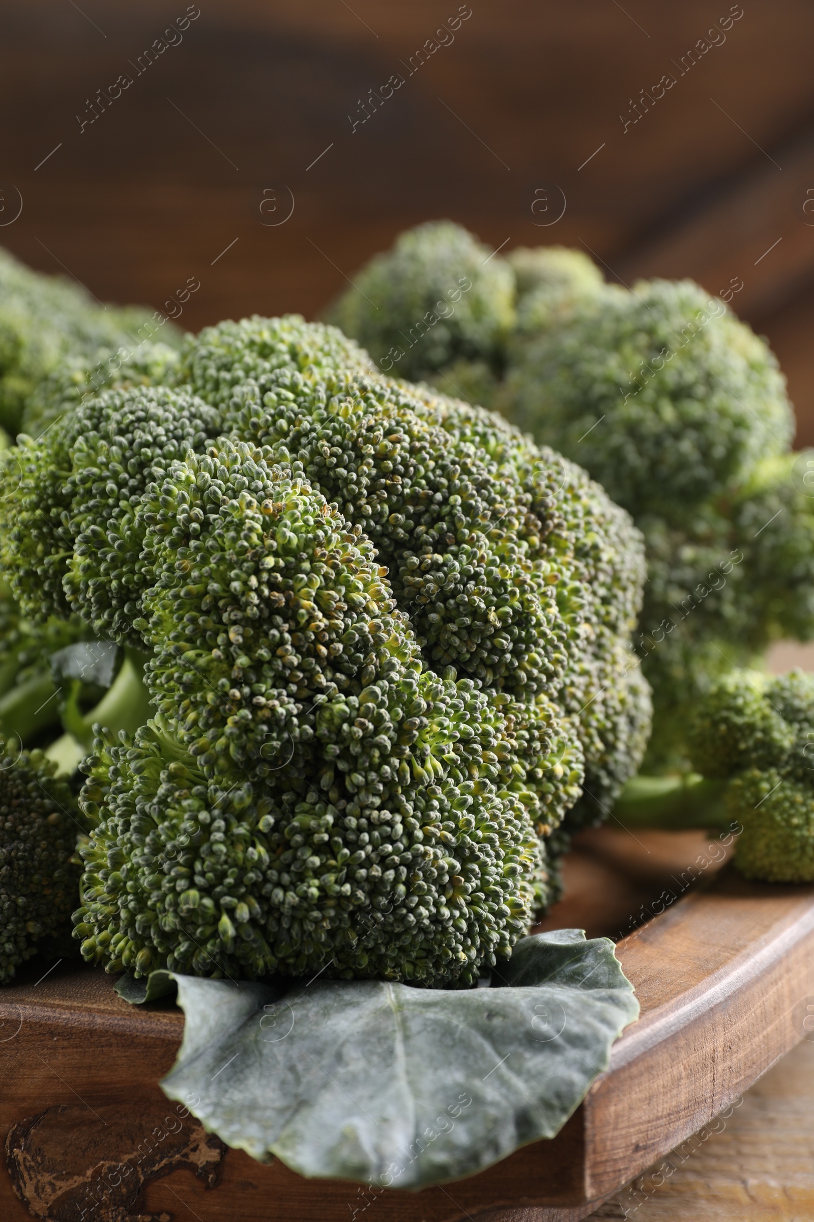 Photo of Wooden tray with fresh raw broccoli on table, closeup