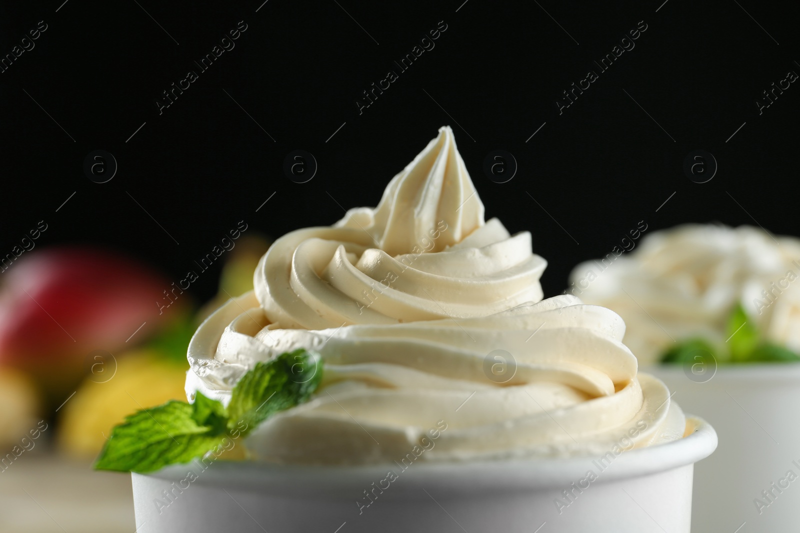 Photo of Cup with tasty frozen yogurt on blurred background, closeup