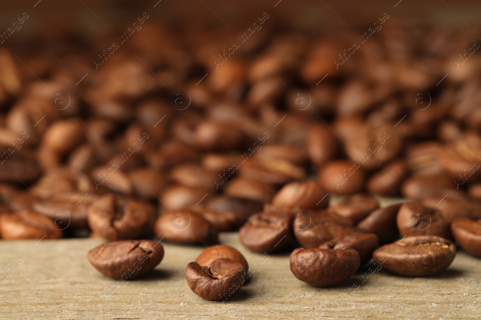 Photo of Many roasted coffee beans on wooden table, closeup