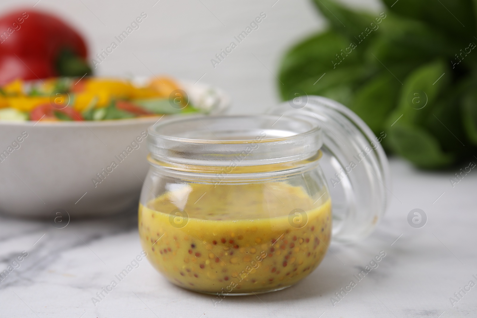 Photo of Tasty vinegar based sauce (Vinaigrette) in jar on white marble table, closeup