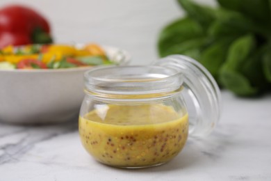 Tasty vinegar based sauce (Vinaigrette) in jar on white marble table, closeup