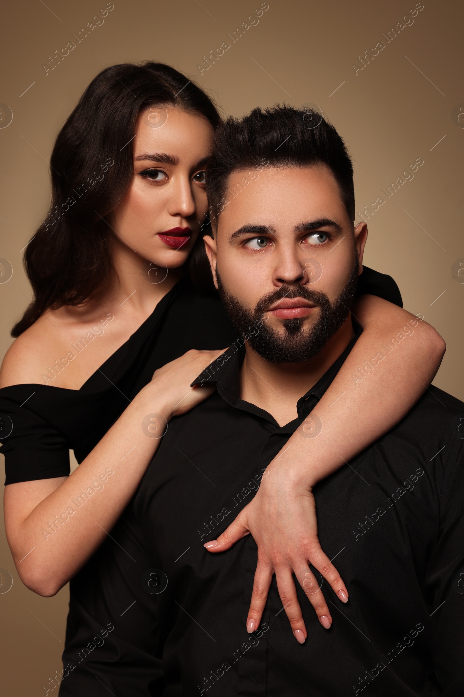 Photo of Handsome bearded man with sexy lady on light brown background