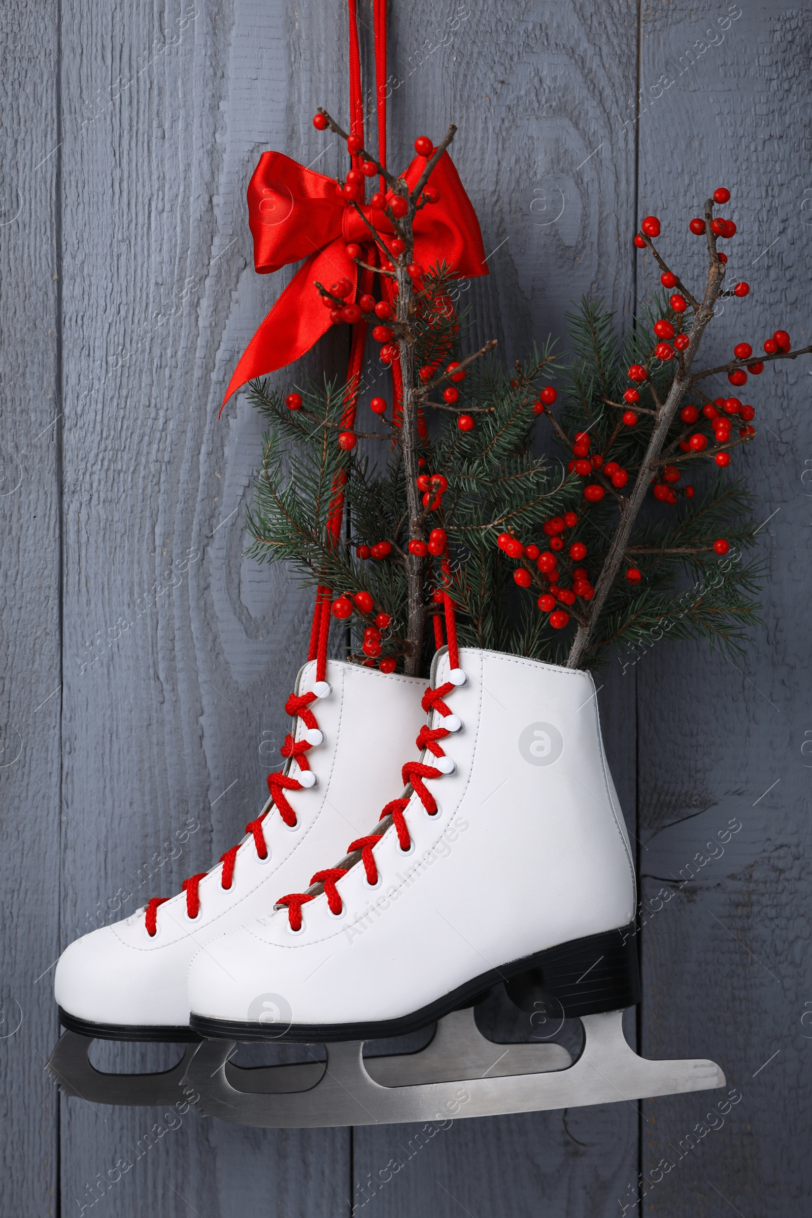 Photo of Pair of ice skates with Christmas decor hanging on grey wooden wall