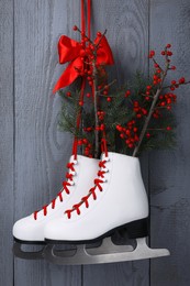 Pair of ice skates with Christmas decor hanging on grey wooden wall