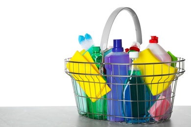 Photo of Shopping basket with different detergents on grey table against white background