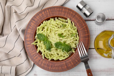 Photo of Plate of delicious trofie pasta with cheese and basil leaves on white wooden table, flat lay