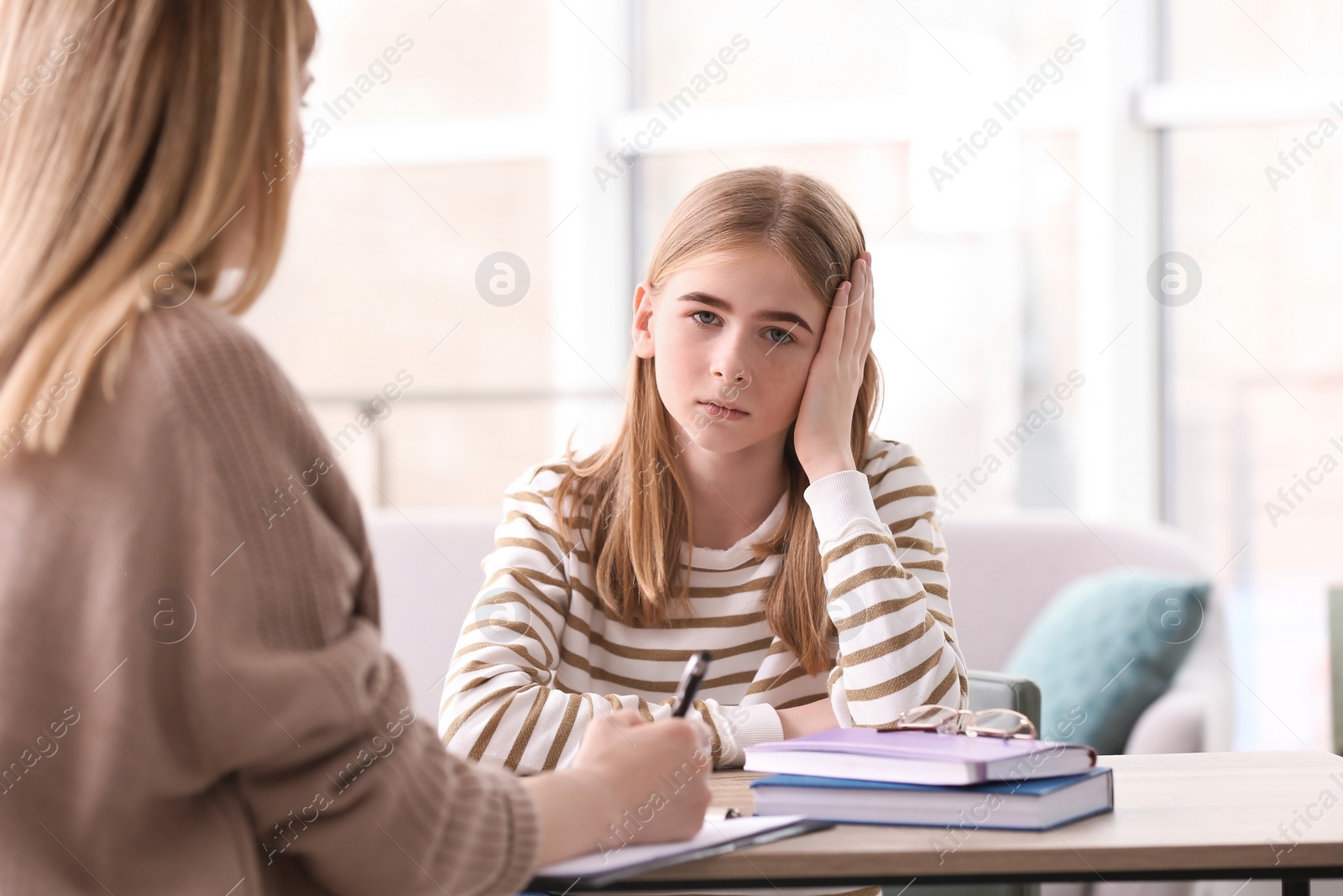 Photo of Young female psychologist working with teenage girl in office