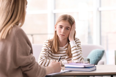 Young female psychologist working with teenage girl in office