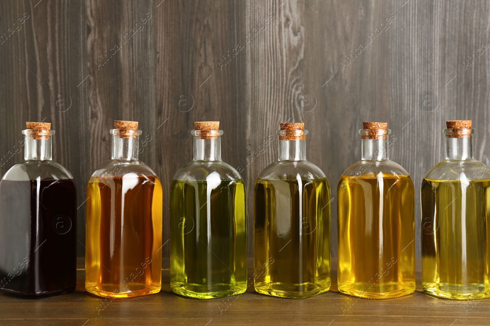 Photo of Vegetable fats. Different oils in glass bottles on wooden table