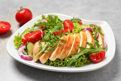 Photo of Delicious salad with meat, arugula and vegetables on grey table, closeup