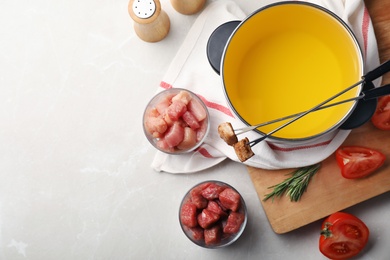 Flat lay composition with fondue pot, meat and space for text on table