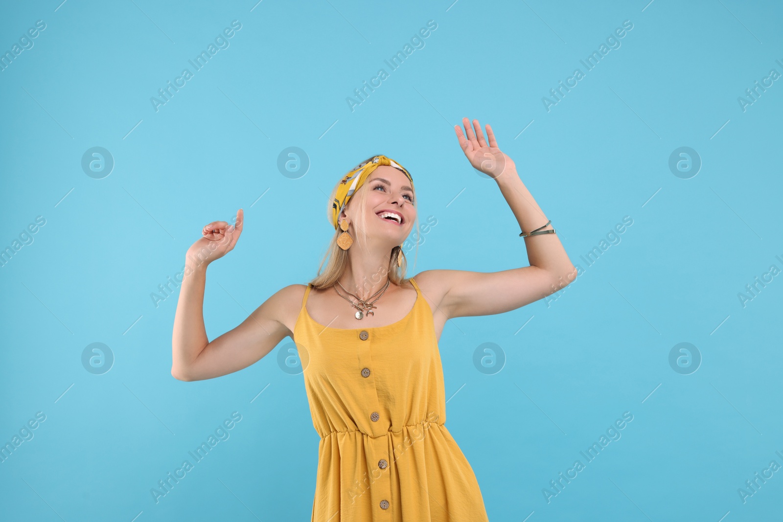 Photo of Portrait of smiling hippie woman dancing on light blue background