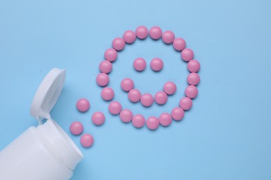 Happy face made of antidepressant pills and bottle on light blue background, flat lay