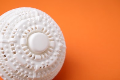 Photo of Laundry dryer ball on orange background, closeup. Space for text