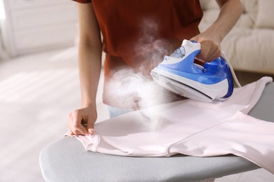 Woman ironing clean laundry with steam, closeup