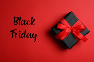 Phrase Black Friday and gift box on red background, top view