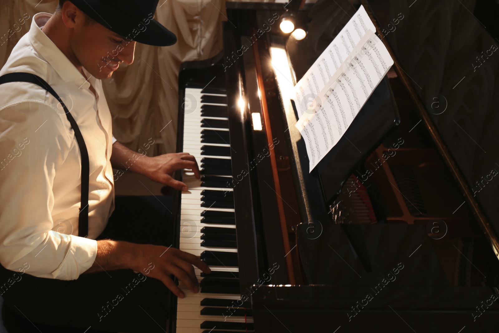 Photo of Man playing grand piano indoors. Talented musician