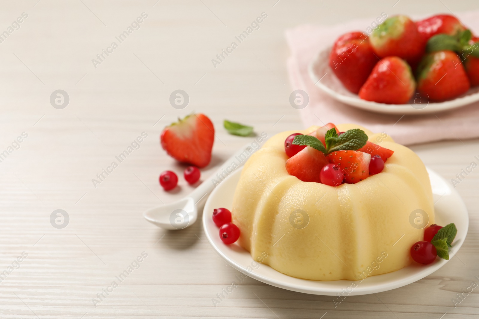 Photo of Delicious semolina pudding with berries on white wooden table, space for text