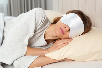 Woman with sleep mask in bed at home