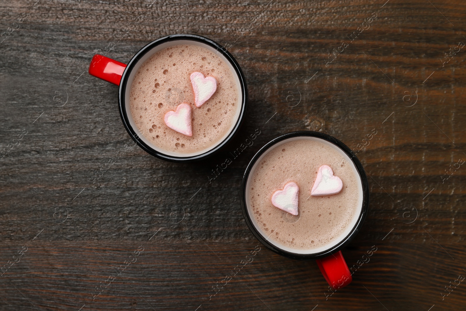 Photo of Cups of aromatic coffee with heart shaped marshmallows on wooden table, flat lay