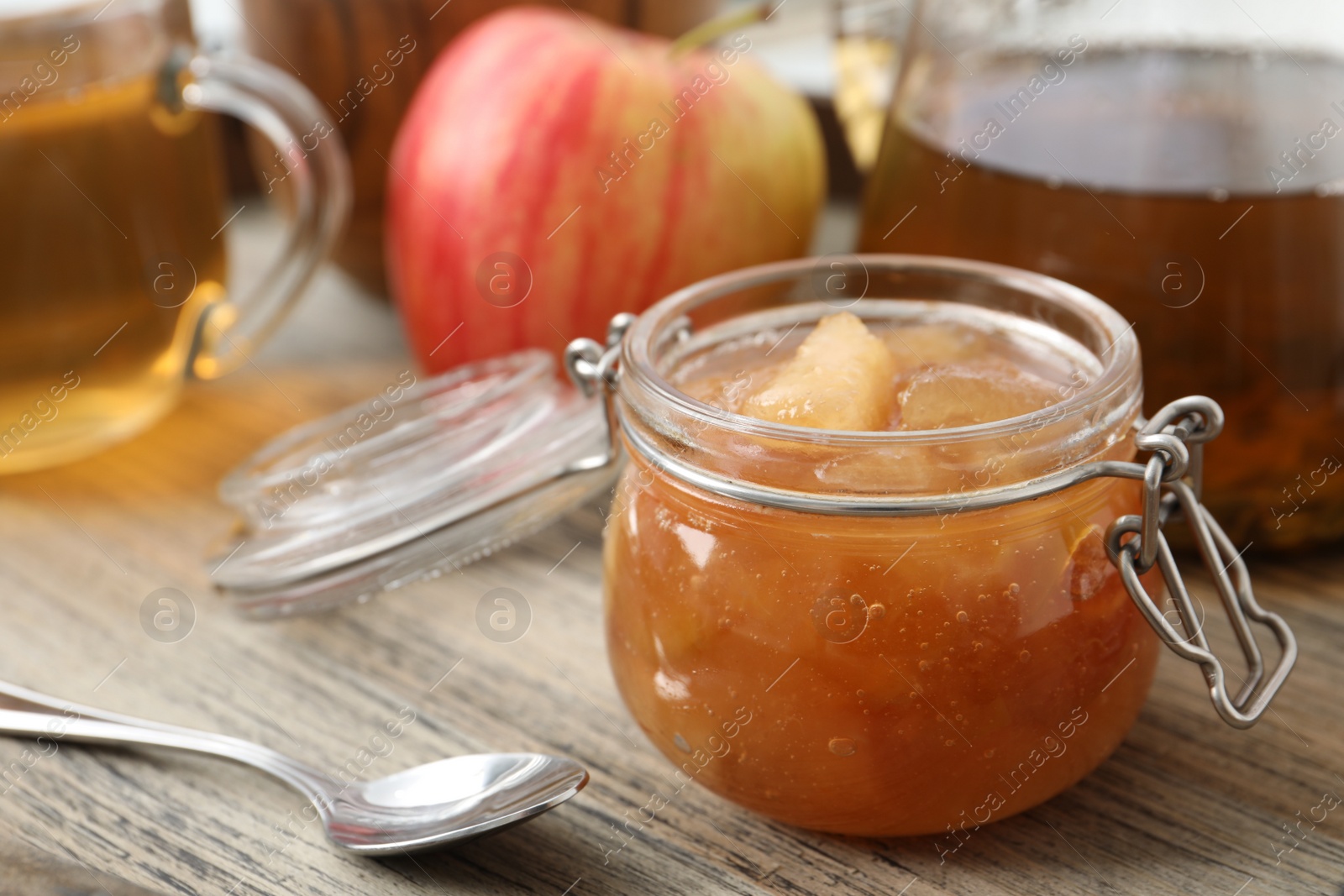 Photo of Delicious apple jam in jar on wooden table, closeup