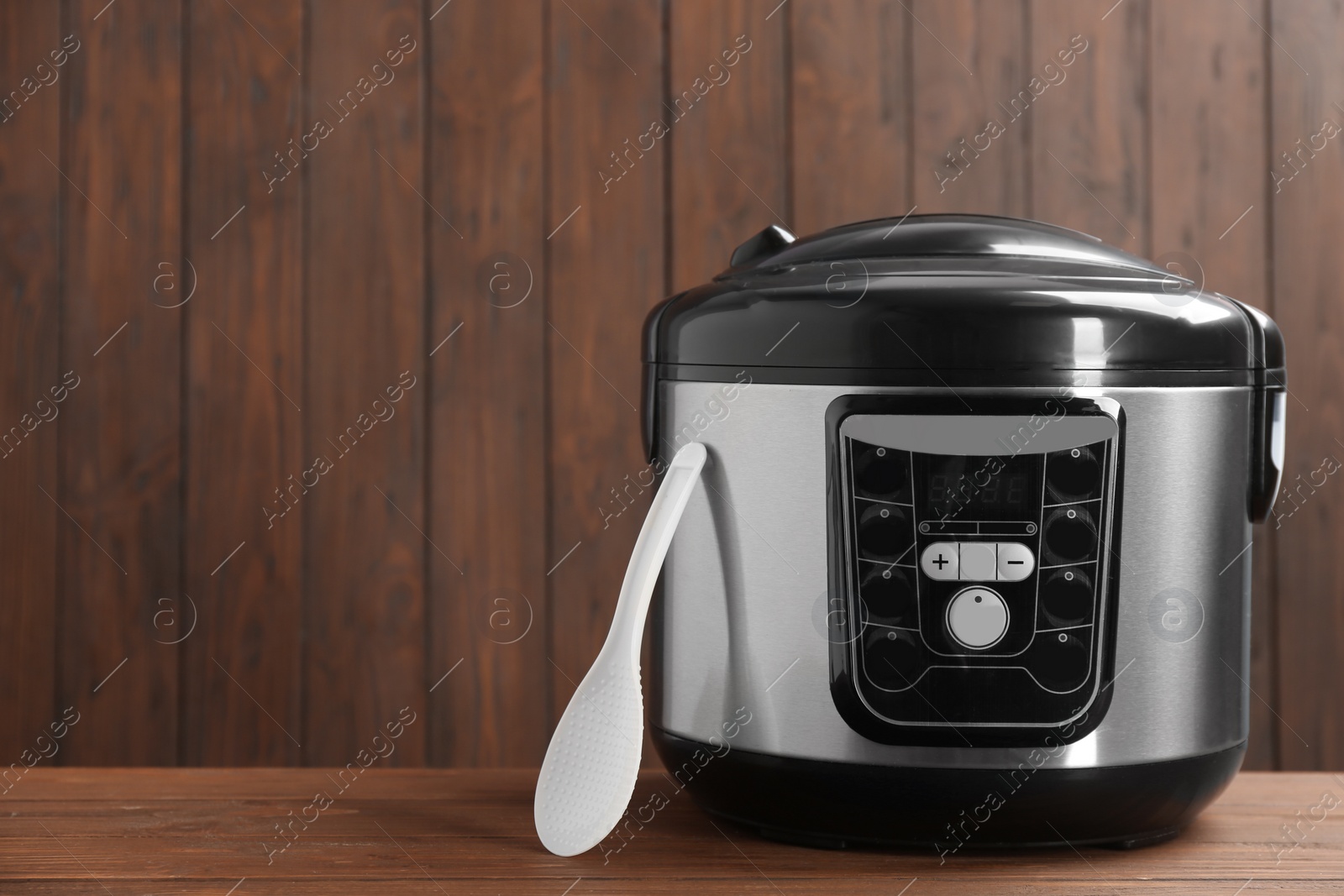 Photo of Modern powerful multi cooker on table against wooden background. Space for text