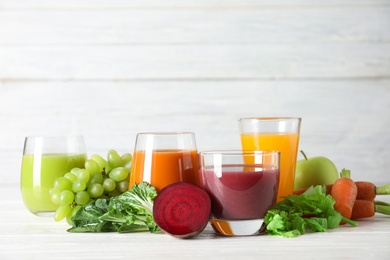 Photo of Glasses with different juices and fresh ingredients on table