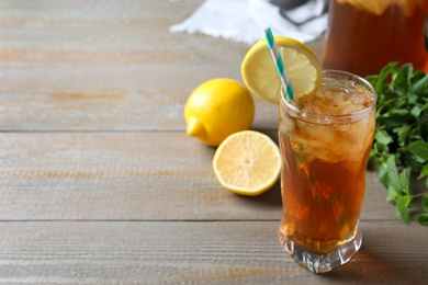 Photo of Delicious iced tea in glass on wooden table, space for text