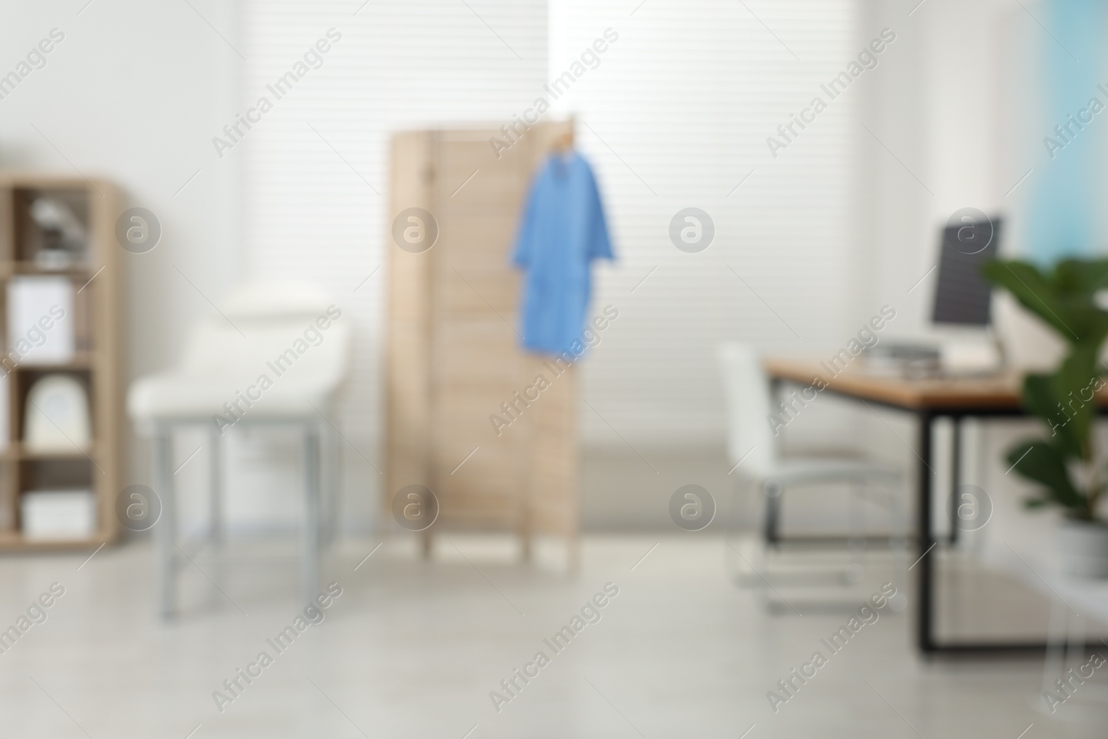 Photo of Blurred view of modern medical office with doctor's workplace and examination table in clinic