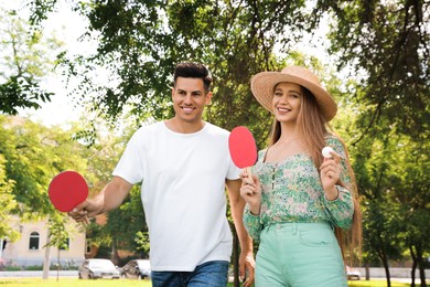 Photo of Happy couple with ping pong rackets and ball in park