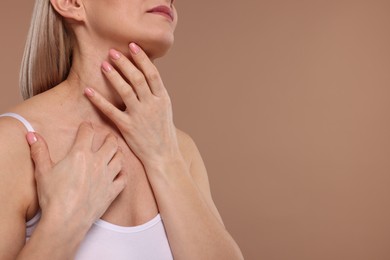 Photo of Woman touching her neck on beige background, closeup. Space for text