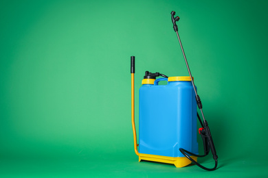 Photo of Manual insecticide sprayer on green background, space for text. Pest control