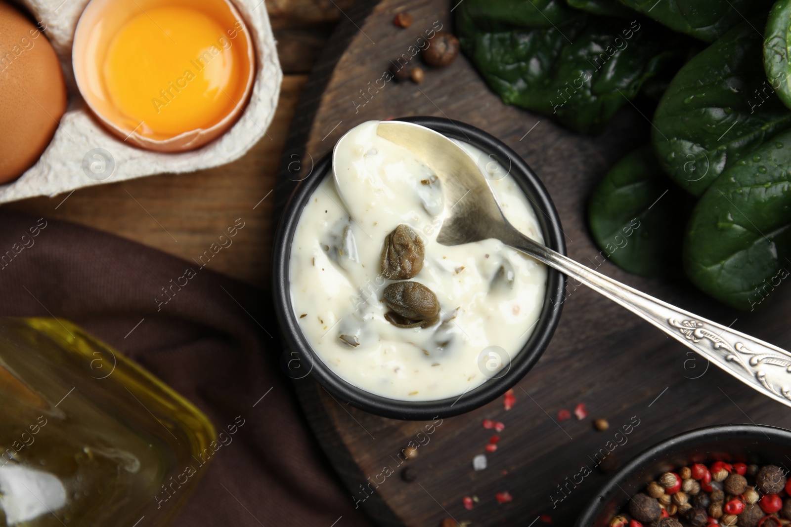 Photo of Caper sauce in bowl and ingredients on wooden table, flat lay