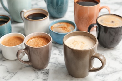 Many cups of different aromatic hot coffee on marble table