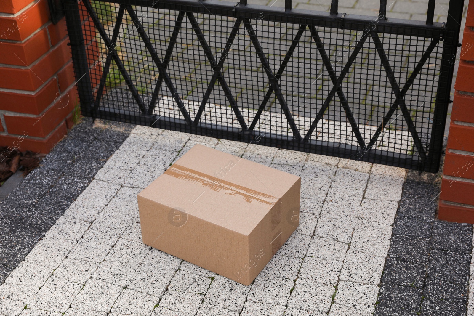 Photo of Cardboard boxes near front gates outdoors. Parcel delivery service