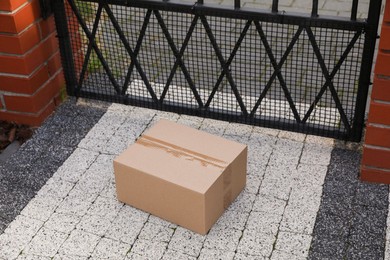 Photo of Cardboard boxes near front gates outdoors. Parcel delivery service