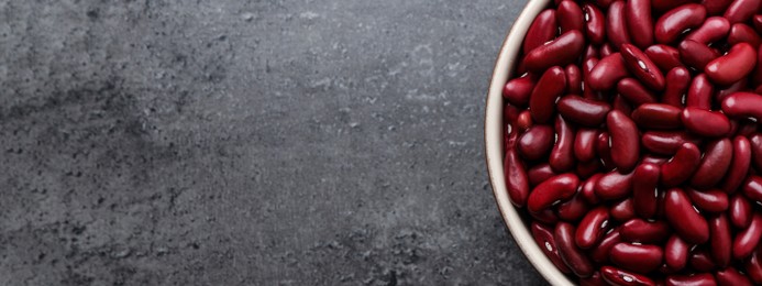 Image of Red kidney beans in bowl and space for text on grey table, top view. Banner design