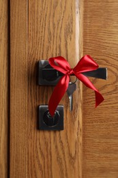 Photo of Key with red bow on door handle. Housewarming party