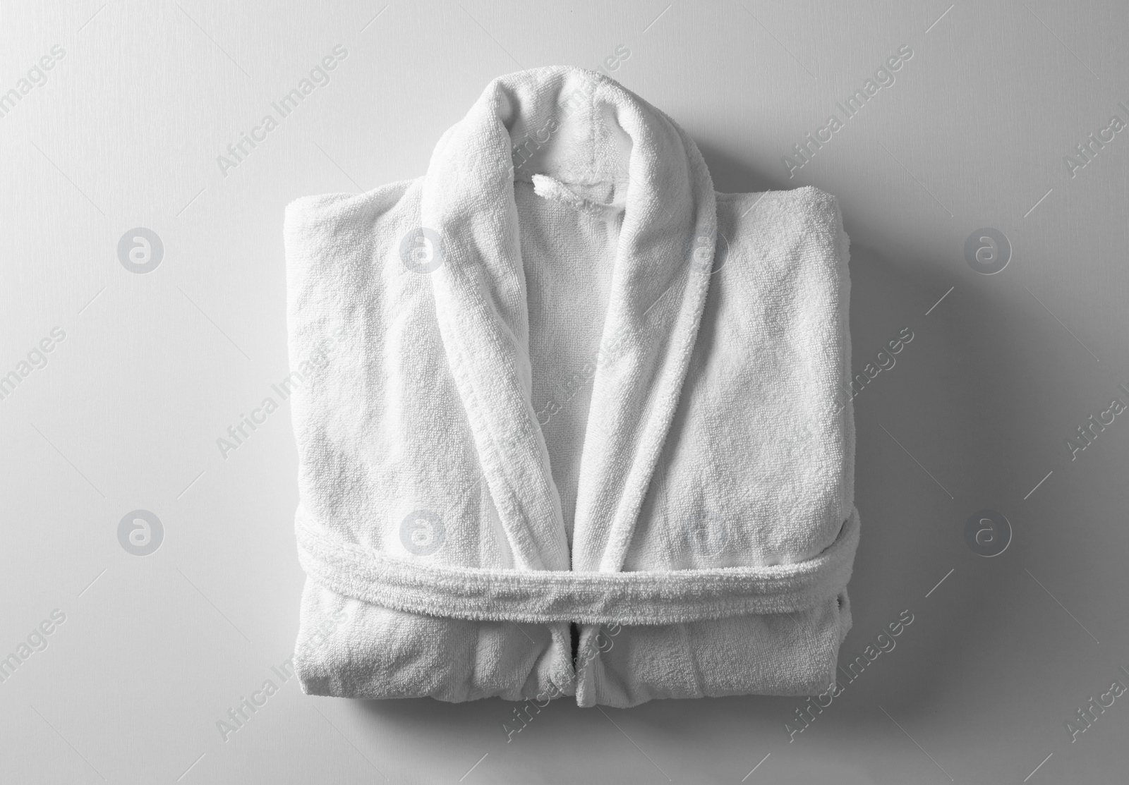 Photo of Clean folded bathrobe on white background, top view