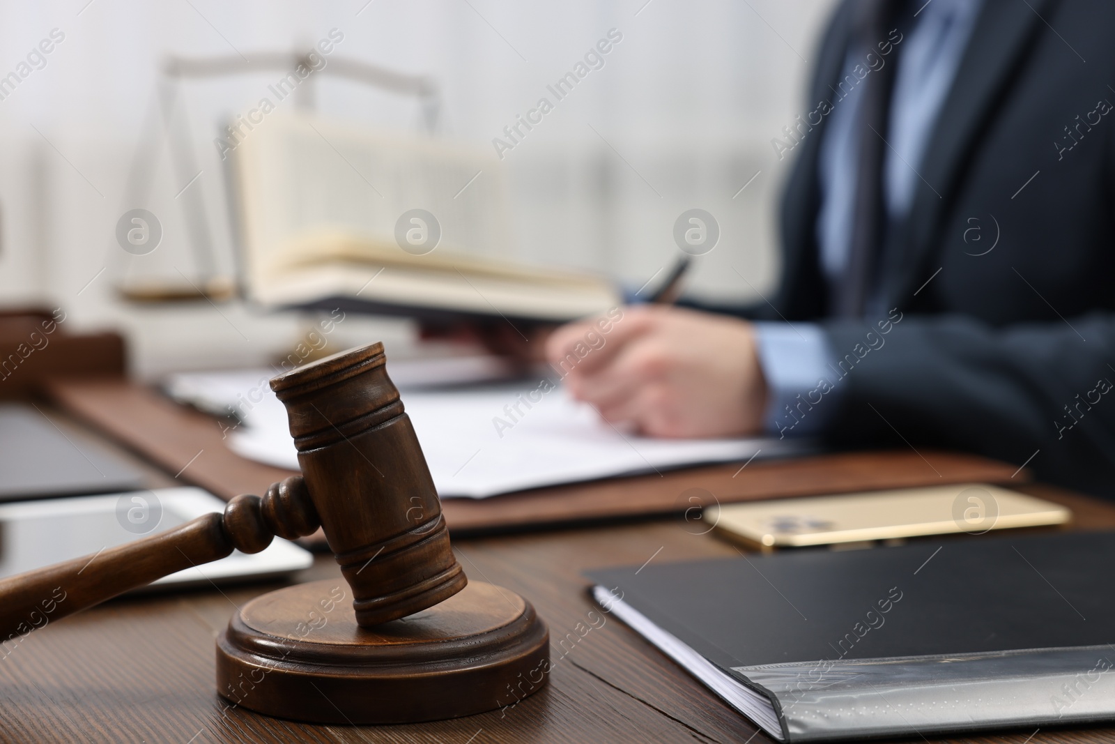 Photo of Lawyer working with documents at wooden table, focus on gavel