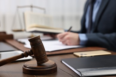 Photo of Lawyer working with documents at wooden table, focus on gavel