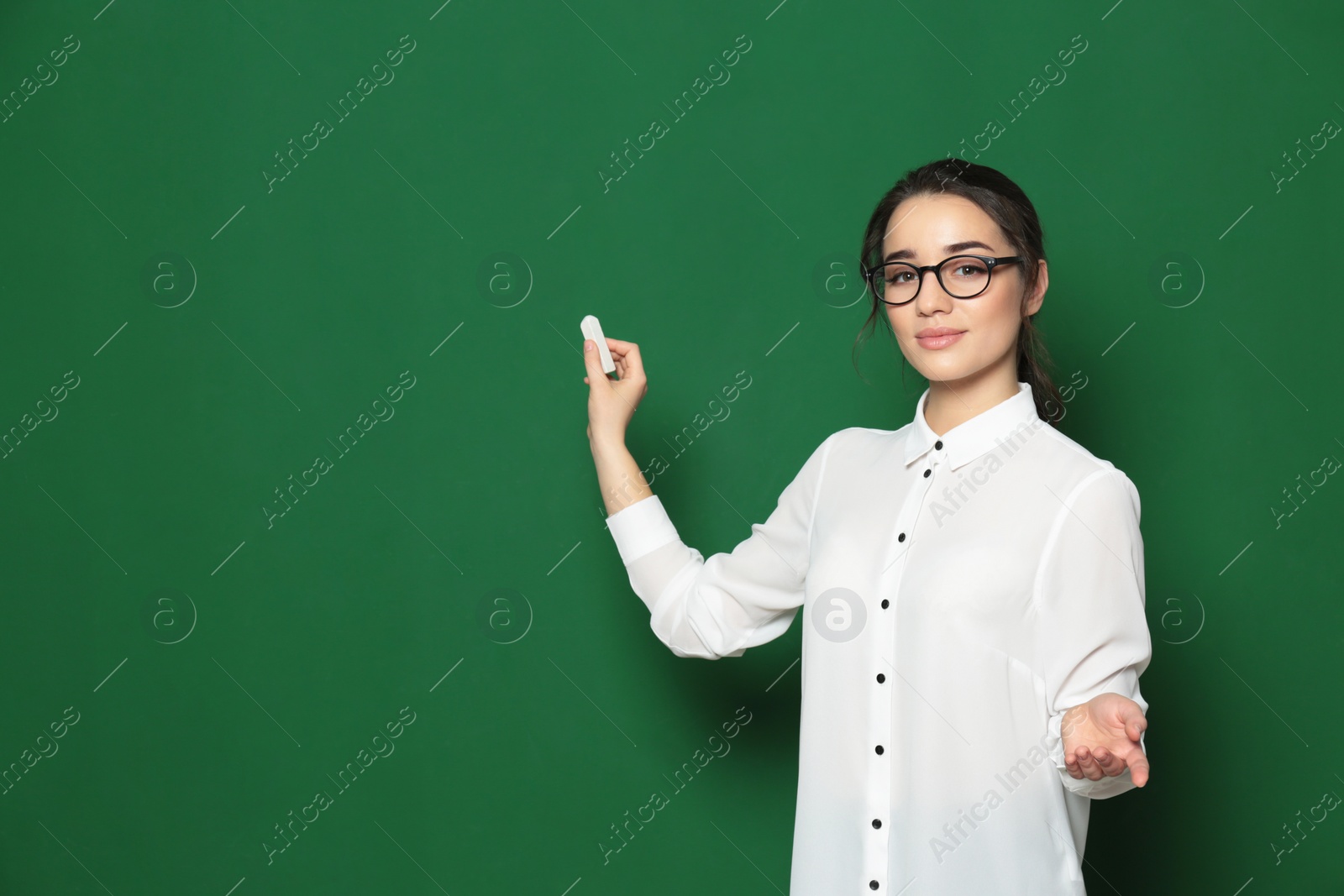 Photo of Portrait of beautiful young teacher near chalkboard, space for text