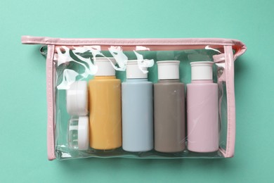 Photo of Cosmetic travel kit in plastic bag on turquoise background, top view. Bath accessories