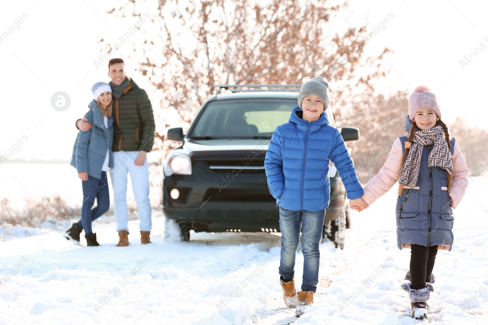 Photo of Cute little brother and sister with parents walking in countryside on winter day